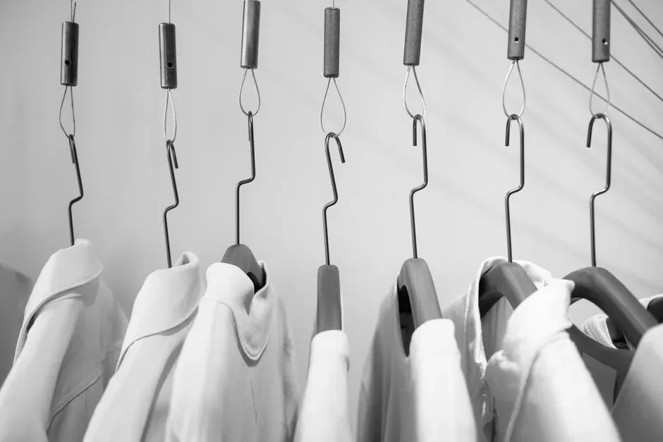 Shirts hanging from ceiling hooks in a store, in black and white