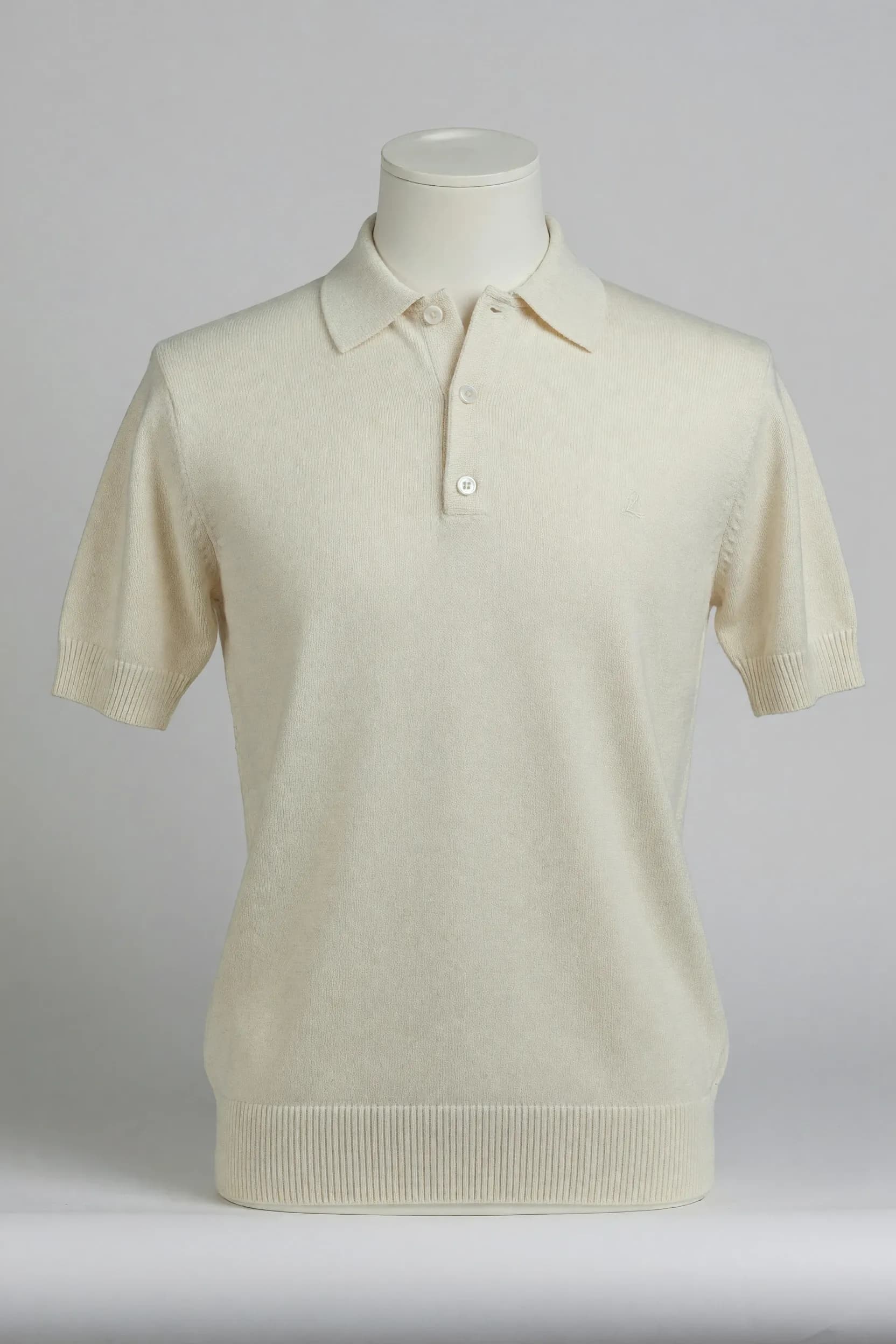 Cream fine-knit three-button short-sleeve polo fitted on a torso mannequin for OEM private-label product development